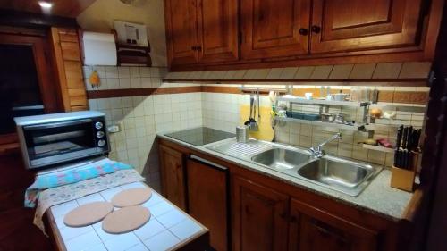 eine Küche mit einer Spüle und einer Mikrowelle in der Unterkunft Chalet Elegante - Campo Felice e Piste da scii in Spogna