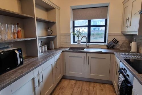 uma cozinha com armários brancos, um lavatório e uma janela em 2 Bed Gated Apartment Westport em Westport