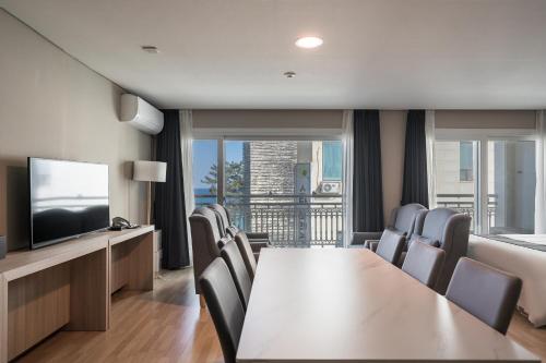 a dining room with a table and chairs and a television at Gyeongpo Soo Hotel in Gangneung