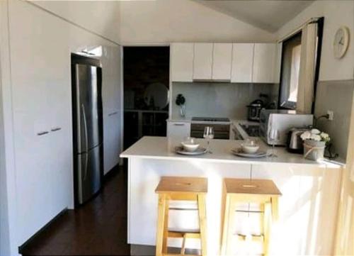 a kitchen with white cabinets and a counter with stools at Lovely Queen Room + TV +Wifi FREE Parking Pet Friendly in Glenfield