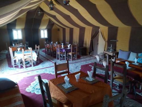 a dining room with tables and chairs in a tent at Khadija Desert Camp in Merzouga