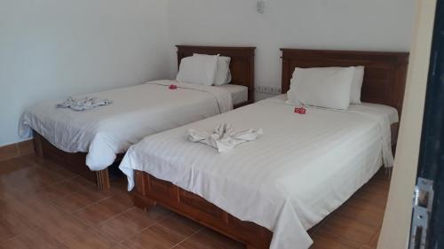 2 letti in una camera con lenzuola bianche di Edo Homestay & Restaurant a Kuta Lombok