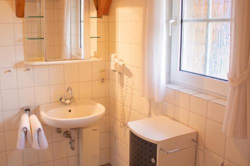 ein weißes Bad mit einem Waschbecken und einem Fenster in der Unterkunft OH 42 - Strandvogt Komfort in Dorum Neufeld