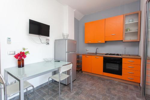 una cucina con armadi arancioni, tavolo e frigorifero di La Casetta Bianca a Praia a Mare