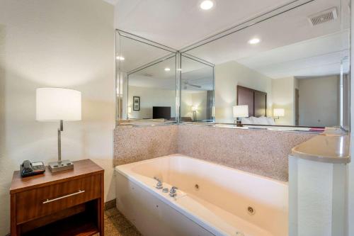 ein Badezimmer mit einer Badewanne und einem großen Spiegel in der Unterkunft Comfort Inn Kissimmee-Lake Buena Vista South in Kissimmee