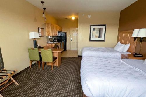 um quarto de hotel com duas camas e uma mesa e uma cozinha em MainStay Suites Williston em Williston