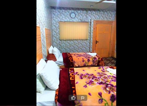 1 dormitorio con 2 camas y reloj en la pared en Prime View Hotel, en Faisalabad