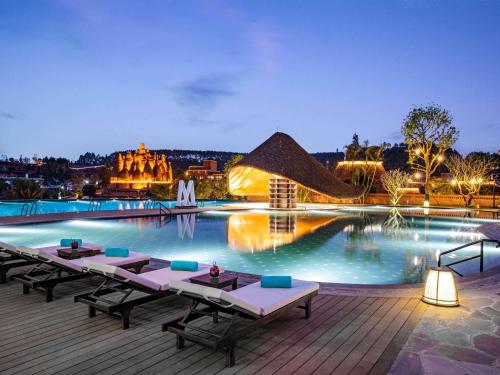 una piscina con mesas en una terraza por la noche en DongFengYun Hotel Mi'Le - MGallery, en Mile