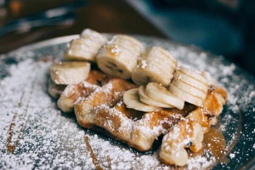 a plate of food with bananas and powdered sugar at Gasthof Hirsch in Schollbrunn