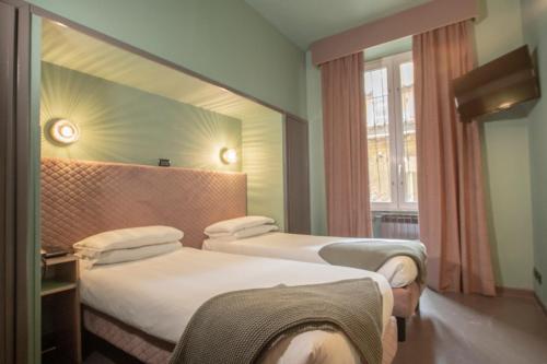 a hotel room with two beds and a window at Hotel Milani in Rome