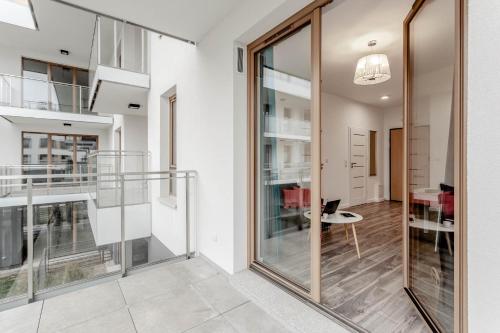 a hallway with glass doors and a dining room at Chill Apartments Wilanów in Warsaw