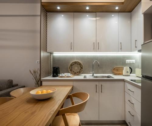a kitchen with white cabinets and a wooden table at IRIS SUITES NIKITI in Nikiti