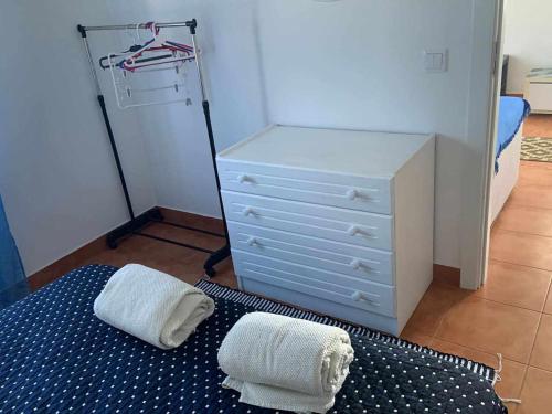 um quarto com uma cómoda e duas toalhas numa cama em Casinha em frente à Lagoa em Aldeia de Brescos