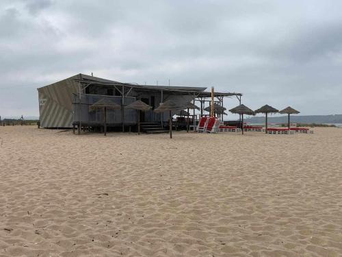 un edificio su una spiaggia con sedie e ombrelloni di Casinha em frente à Lagoa ad Aldeia de Brescos
