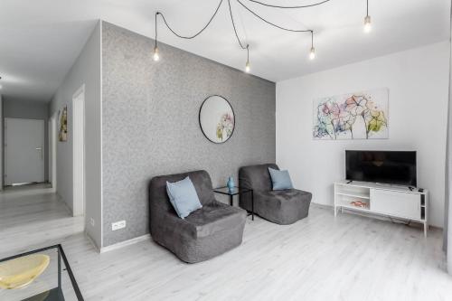 a living room with two chairs and a flat screen tv at Chill Apartments Bociania in Warsaw