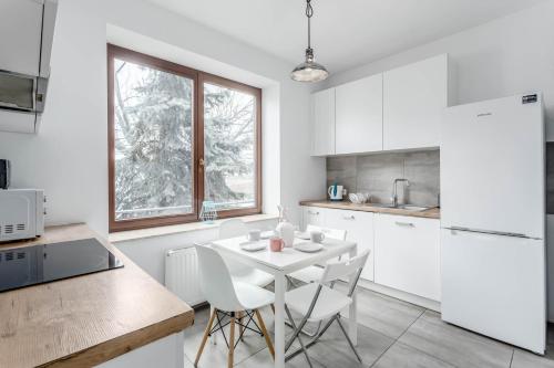 a white kitchen with a white table and chairs at Chill Apartments Bociania in Warsaw
