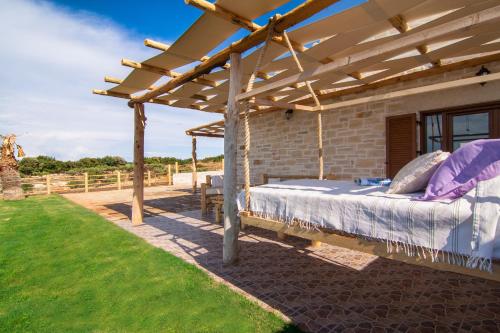 Bett unter einer hölzernen Pergola im Hof in der Unterkunft Chainteris Villas, a Summer Dream, By ThinkVilla in Prínos