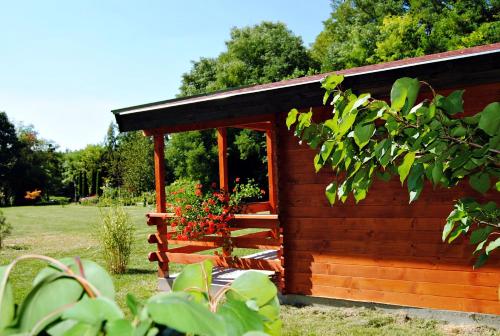 a small wooden cabin with a porch and flowers at Villa Hedi Vendégház in Dunakiliti