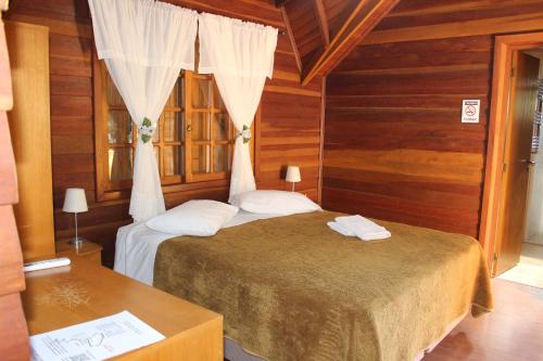 a bedroom with two beds in a room with wooden walls at Pousada Floresta Negra in Canela