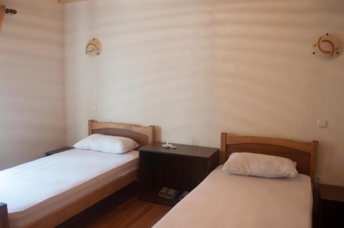 a room with two beds and a nightstand between them at Aste Guesthouse in Tropojë