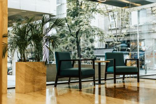 a table and chairs in a lobby with plants at MARK Hotel in Belgrade