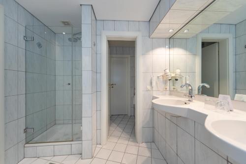 梅拉納的住宿－Hotel Meerane，带淋浴、盥洗盆和镜子的浴室