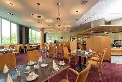 um restaurante com mesas e cadeiras e uma cozinha em Hotel Meerane em Meerane