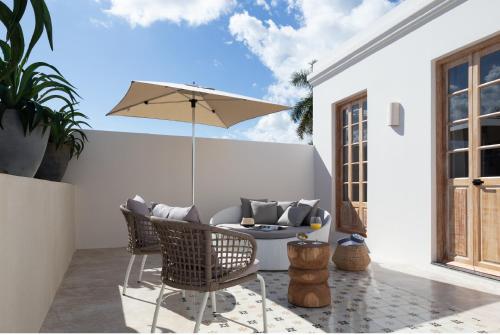 a patio with a table and an umbrella at Más Palomas Concept House by Paloma's Hotels - Adults Only in Mérida