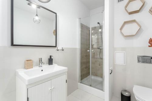 a white bathroom with a sink and a shower at Chill Apartments Bociania in Warsaw