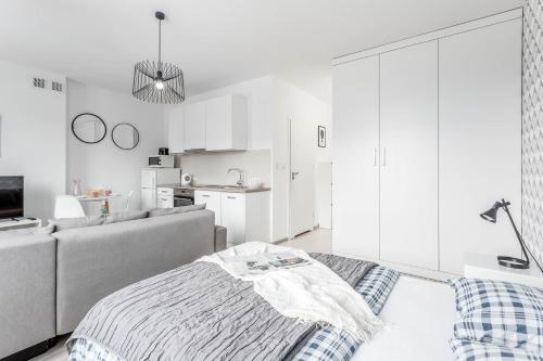 a white living room with a couch and a kitchen at Chill Apartments Bociania in Warsaw