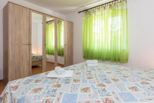 a bedroom with a large bed with green curtains at Apartments Hodanić in Krk