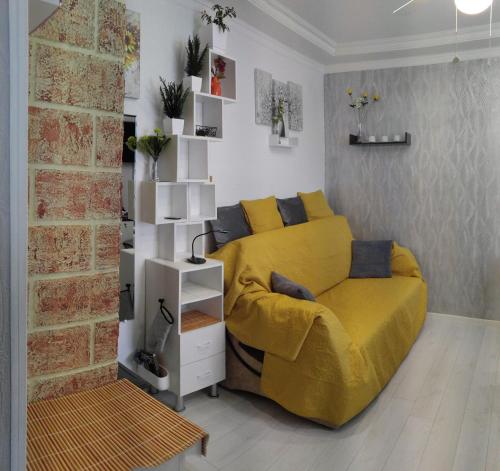a bedroom with a yellow bed and a brick wall at Frendly Flat Free Parking Kitchen Equipment Cosy in Rīga