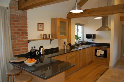 una cocina con encimeras negras y armarios de madera en Honeysuckle Farm cottages, en Glastonbury