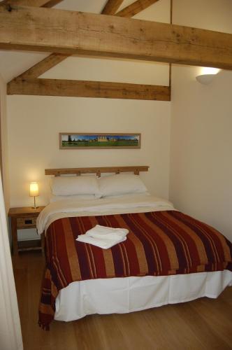a bedroom with a large bed with a wooden ceiling at Honeysuckle Farm cottages in Glastonbury