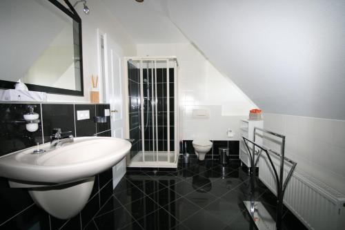 a black and white bathroom with a sink and a mirror at Ferienwohnungen Wyk/Föhr in Wyk auf Föhr