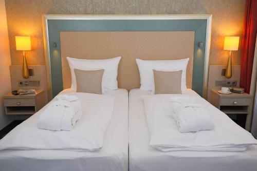 a large bed with white sheets and pillows at Hotel Bayerischer Hof Miesbach, BW Premier Collection in Miesbach