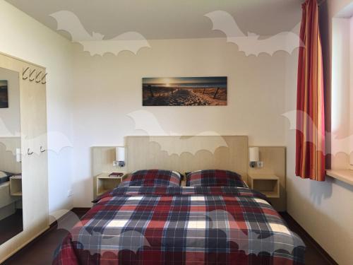 ein Schlafzimmer mit einem Bett mit einer karierten Decke in der Unterkunft Ferienwohnung Fledermaus in Gelbensande