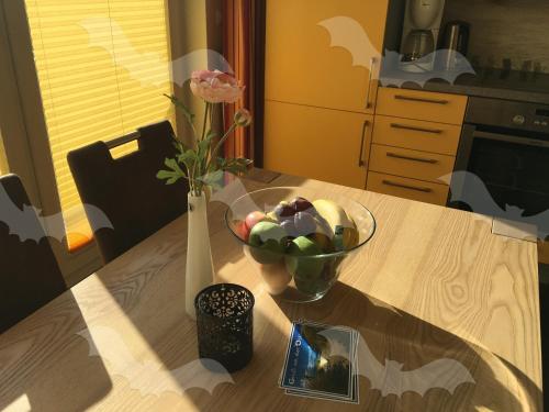 einen Tisch mit einer Schale Obst und einer Vase Blumen in der Unterkunft Ferienwohnung Fledermaus in Gelbensande