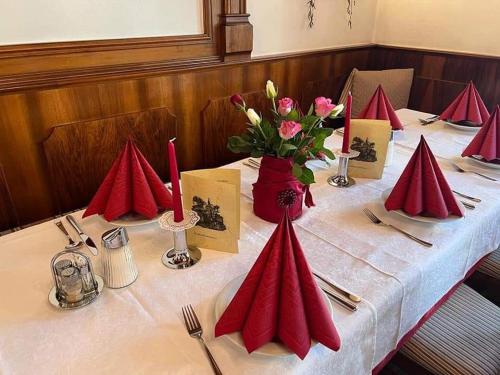 グミュント・イン・ケルンテンにあるHotel Gasthof Kohlmayrの赤いナプキンと花のテーブル