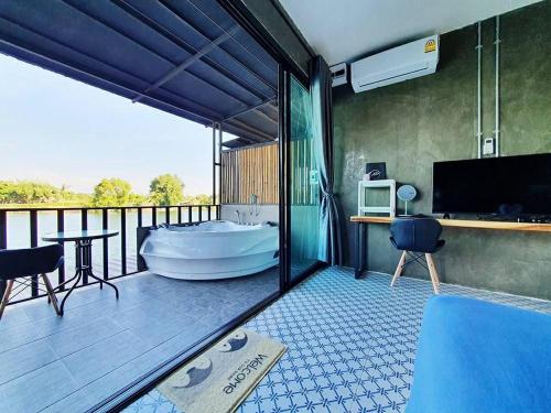 a bathroom with a tub and a balcony with a tv at Kram Farmstay in Nakhon Pathom