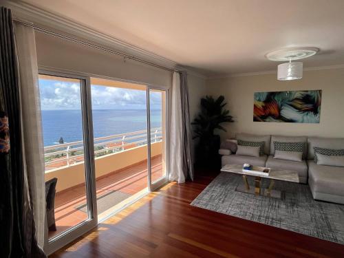een woonkamer met een bank en uitzicht op de oceaan bij All Warmth - Colinas do Lido in Funchal