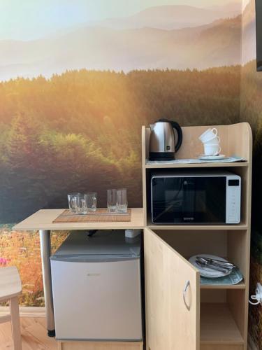 a kitchen with a table with a microwave and a painting at Гостьовий двір РіОНІ in Truskavets