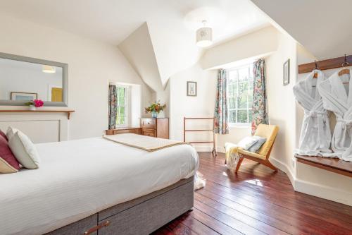 a bedroom with a large bed and a chair at Gardener's Cottage in Crieff