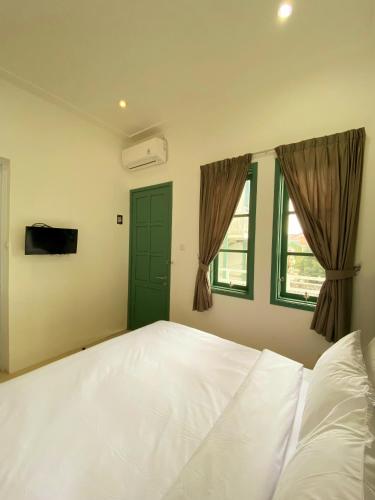 una camera da letto con un grande letto bianco e una finestra di BINUMAR GUEST HOUSE PEKALONGAN a Pekalongan