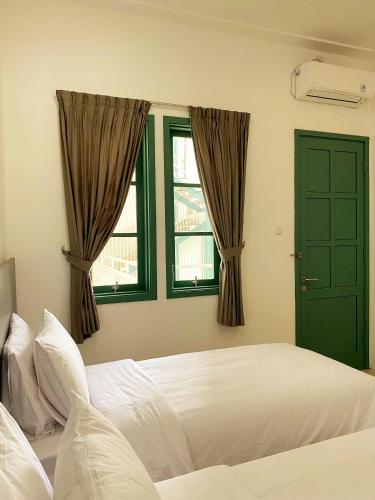 una camera con un letto bianco e due finestre di BINUMAR GUEST HOUSE PEKALONGAN a Pekalongan