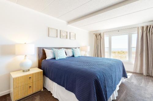Un dormitorio blanco con una cama azul y una ventana en Sandpiper Dunes 105 en Ocean City