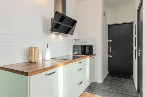 une cuisine avec des placards blancs et une porte noire dans l'établissement Le Selah, à Tourcoing