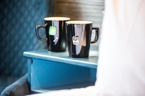ボーンマスにあるNo5 Durley Road - Contemporary serviced rooms and suites - no food availableの青いテーブルに座ったブラックコーヒーマグカップ2つ