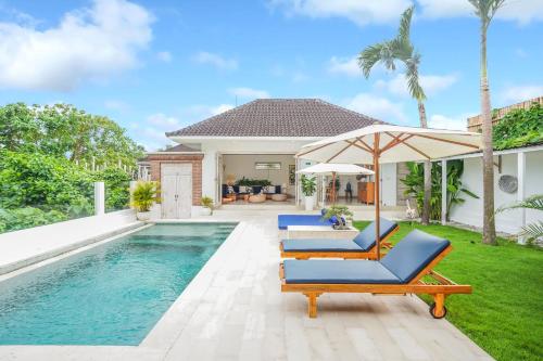 een zwembad met 2 stoelen en een parasol naast een huis bij Villa Bonsai Kecil Pererenan in Munggu