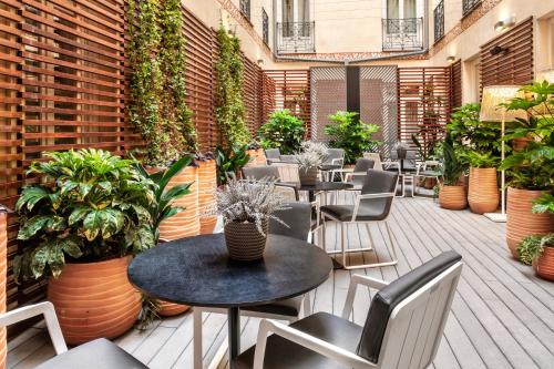 an outdoor patio with tables and chairs and plants at Catalonia Plaza Mayor in Madrid